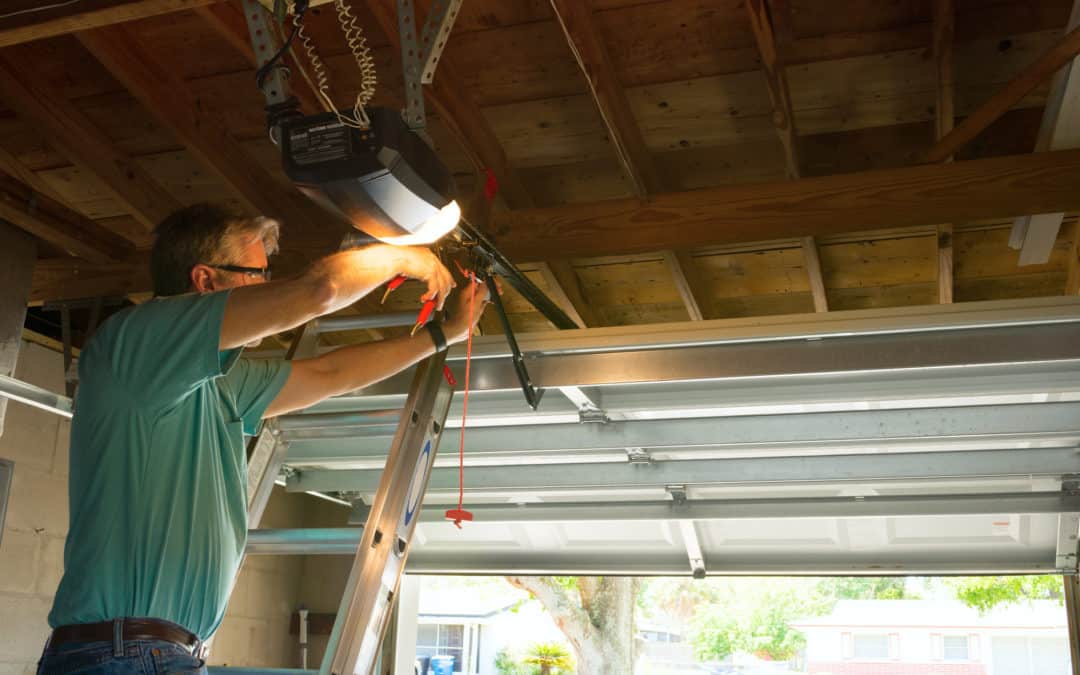 Professional automatic garage door opener repair service technician man working on a ladder at a home residential location making adjustments and fixing it